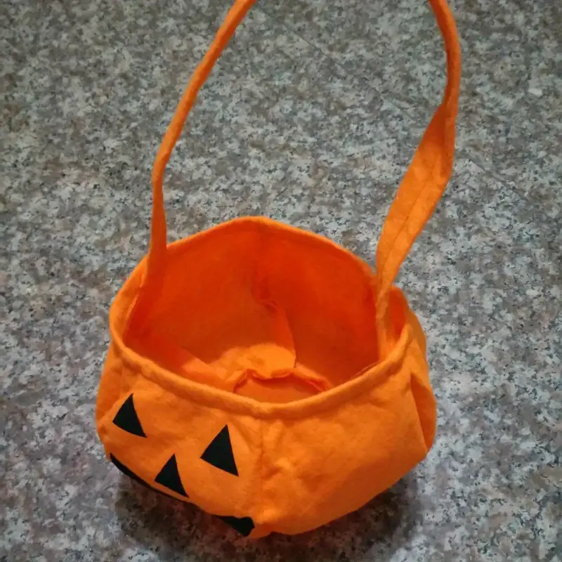 Cesta ligera naranja para dulces de Halloween con diseño de calabaza, dos asas altas y cara impresa.