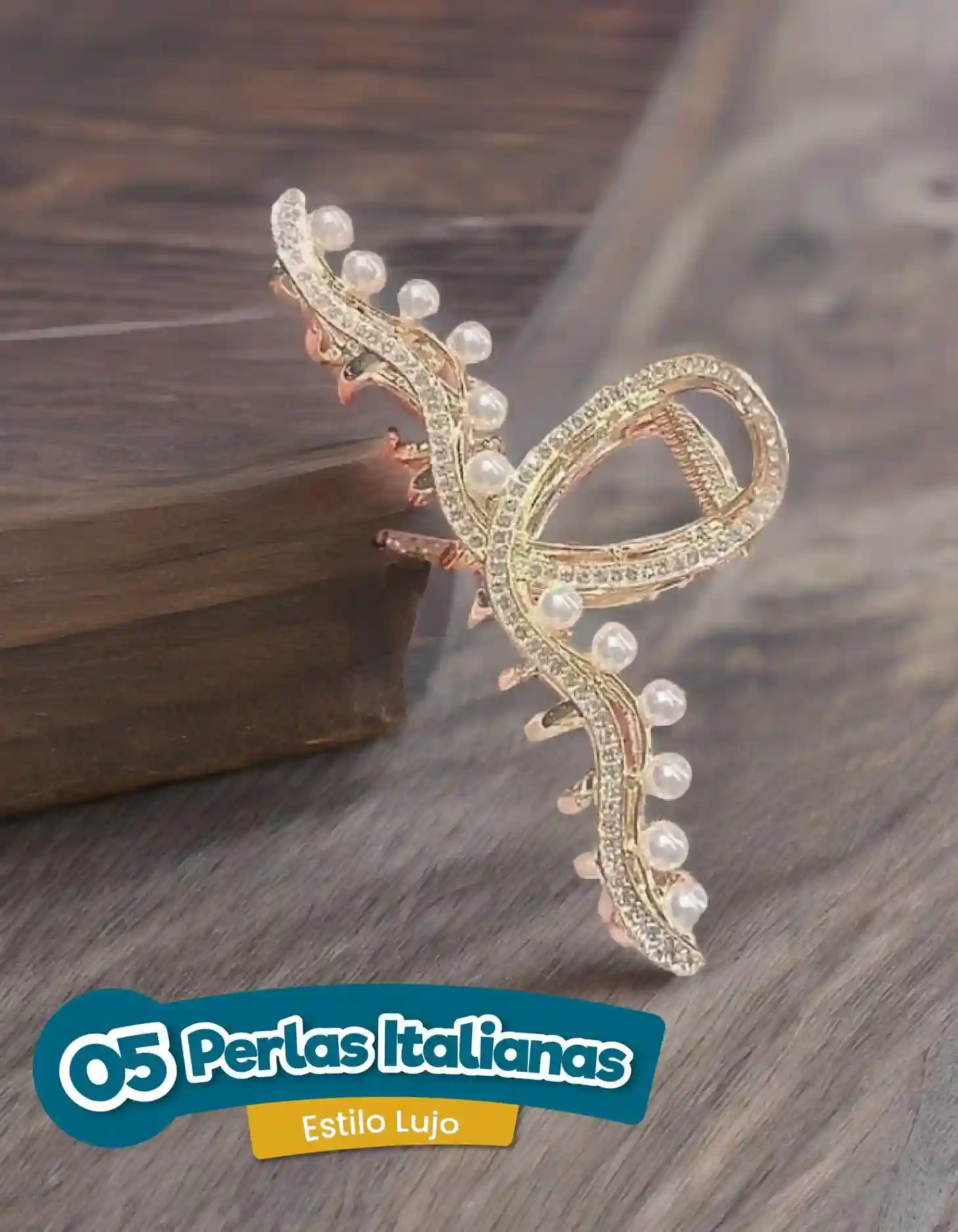 Pinza para el cabello dorada con incrustaciones de brillantes y perlas blancas, diseño curvo elegante apoyada sobre una superficie de madera.
