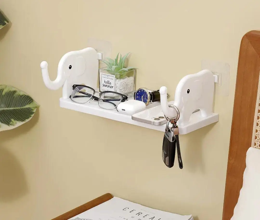 Estante flotante de pared blanco en ABS con diseño de elefante y adhesivo, que sostiene gafas, llaves, reloj y un pequeño cactus.