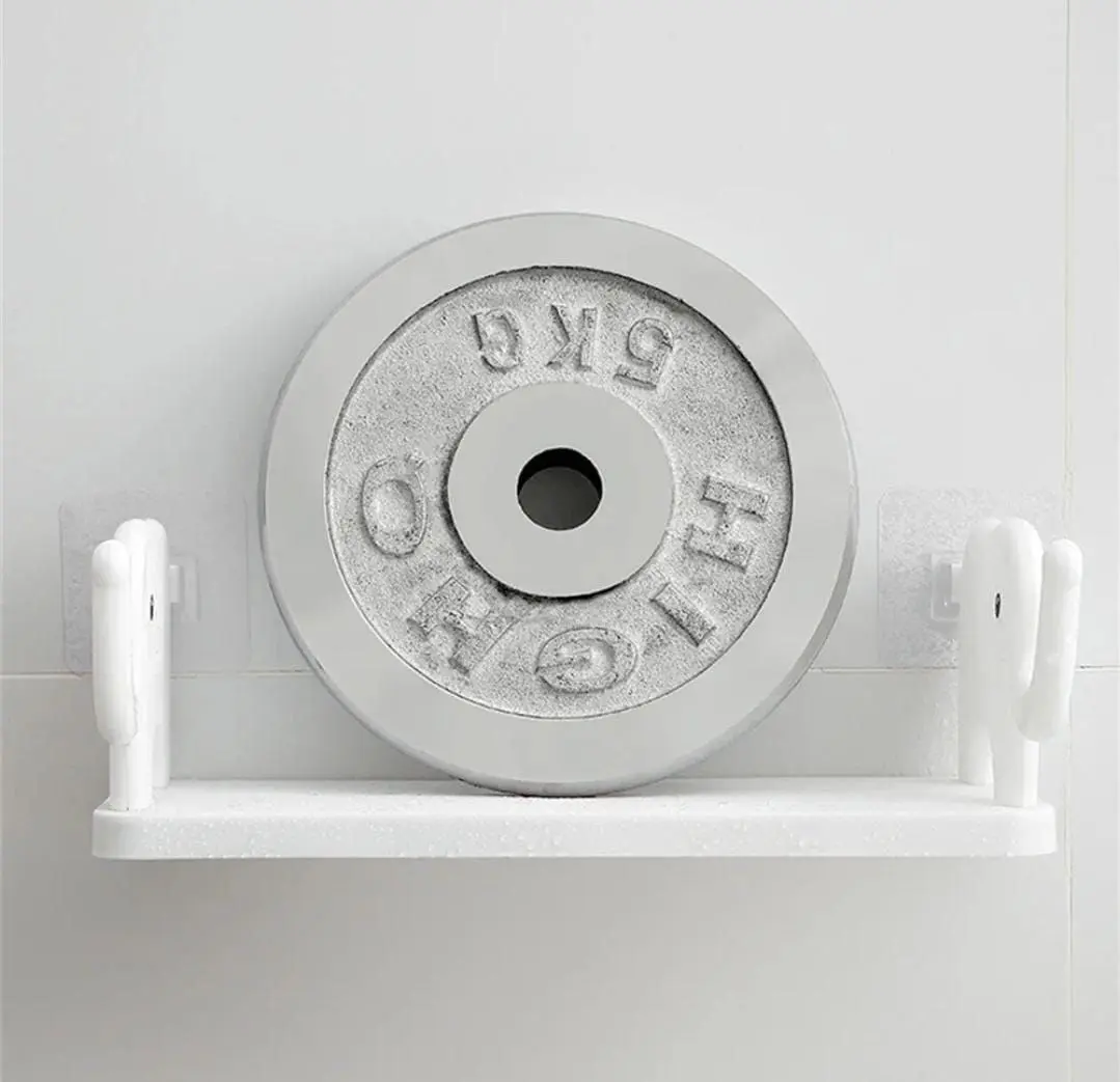 Estante de pared blanco con diseño de elefantes en los extremos, instalado con adhesivo transparente y soportando un disco de pesas de 5 kg.