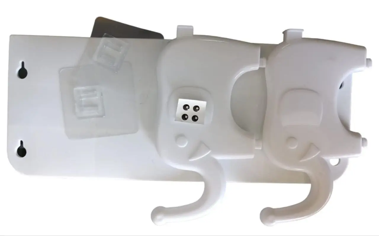 Set de dos ganchos adhesivos de pared blancos en forma de elefante con trompa curva, sobre base plástica y láminas adhesivas transparentes incluidas.
