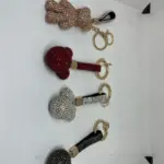 Set de cuatro llaveros metálicos con cristales brillantes incrustados, organizados verticalmente en colores dorado, rojo, plateado y negro.