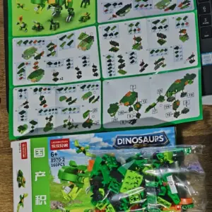 Caja de bloques de construcción verdes para armar un dinosaurio tipo T-Rex, con bolsa de piezas plásticas y manual de instrucciones desplegado sobre superficie de madera.