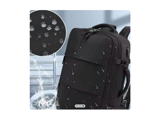 Mochila de viaje negra impermeable con gotas de agua en la superficie, puerto USB frontal y detalle de la textura repelente al agua.