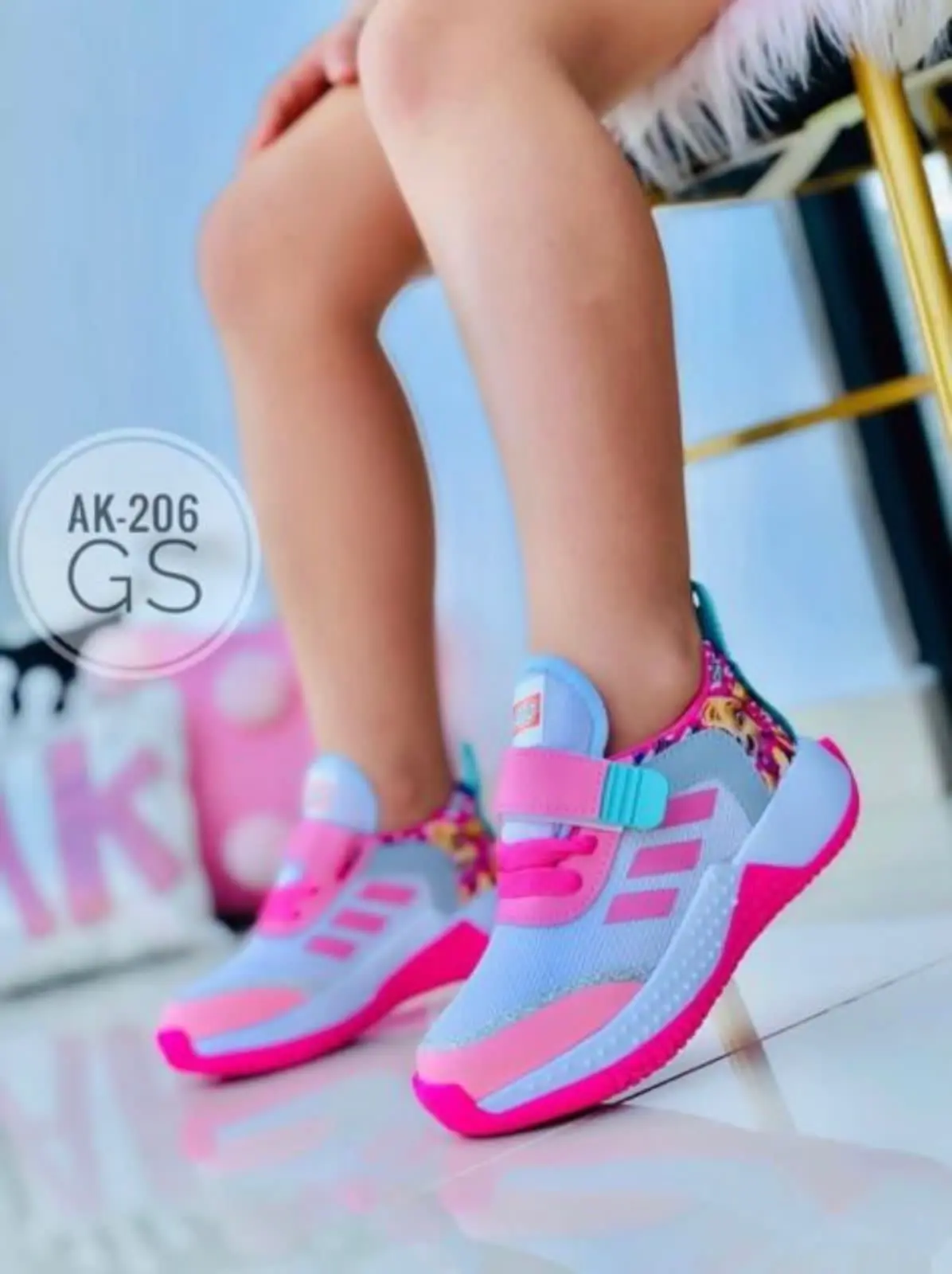 Zapatillas deportivas infantiles azul claro y fucsia con detalles florales en el talón, cordones y correa de velcro para un ajuste cómodo.