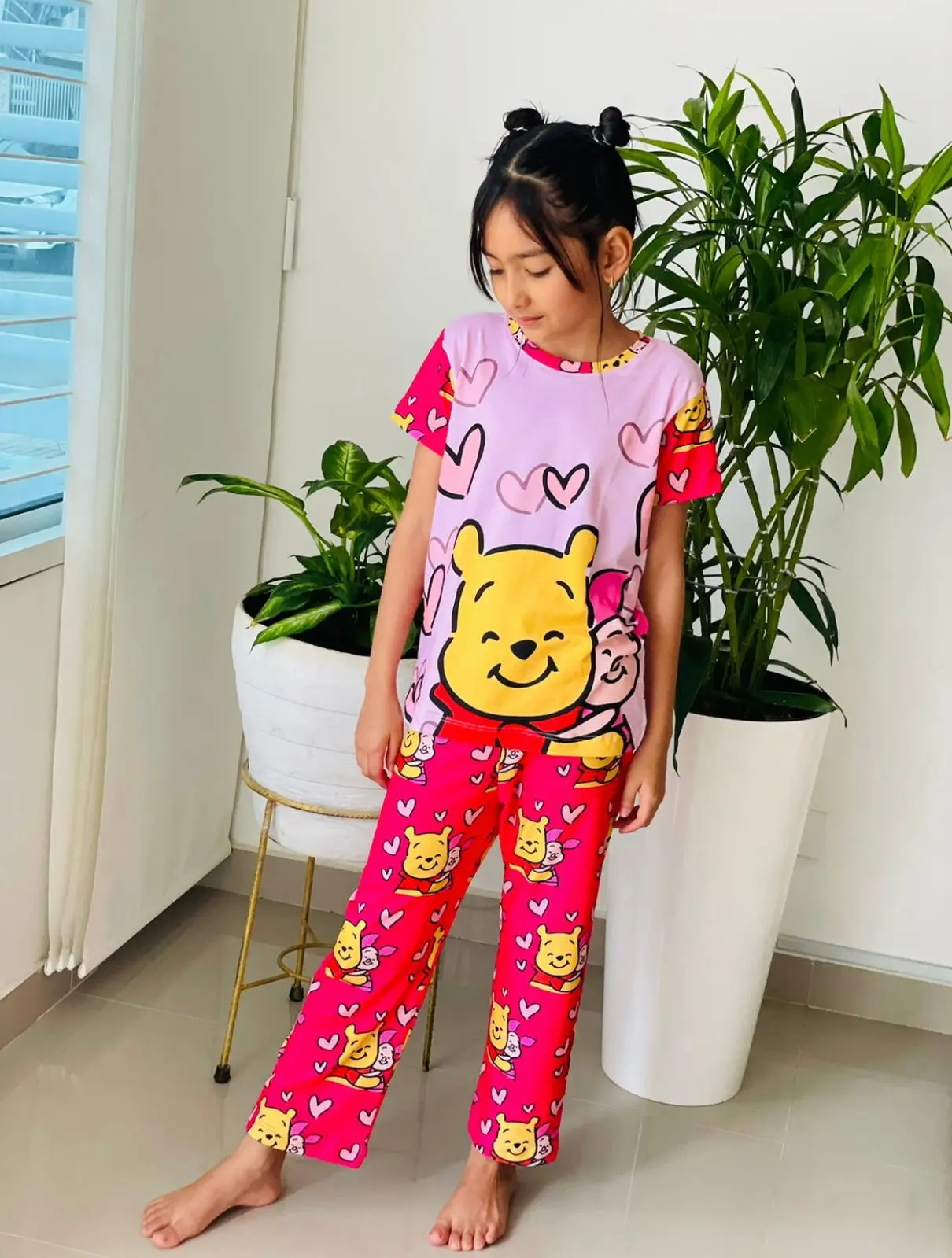 Pijama infantil de dos piezas fucsia y lila con estampado de Winnie the Pooh, elaborada en tela suave para descanso.