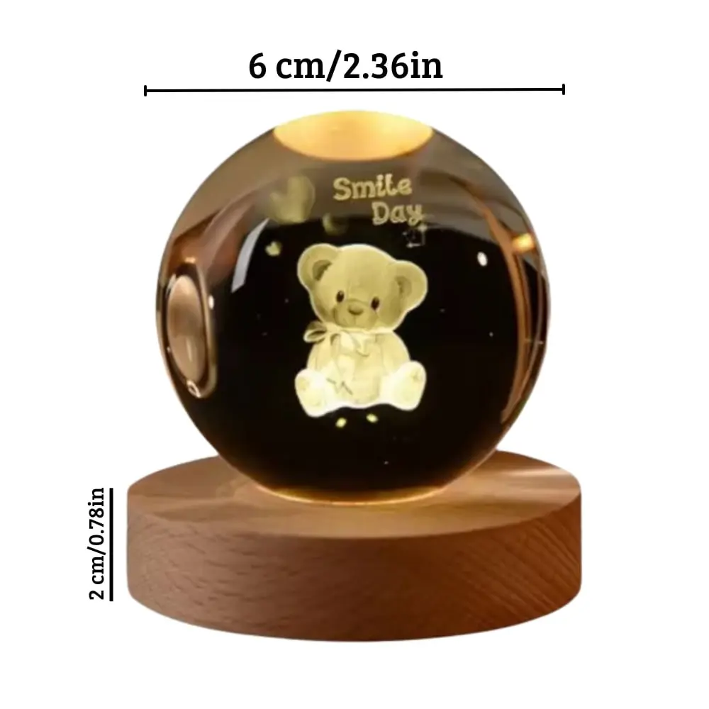 Esfera de cristal con oso grabado de 6 cm de diámetro y base de madera iluminada con luz cálida ambiental.