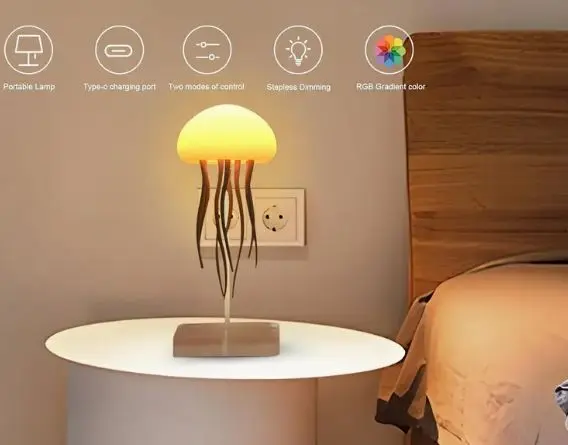 Lámpara LED decorativa con forma de medusa y luz cálida, con base cuadrada y tentáculos oscuros, sobre una mesa de noche en un dormitorio.