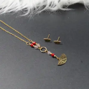 Set de collar corbatín y aretes dorados con cuentas de murano rojas y dije de media luna grabada.