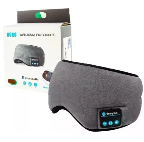 Antifaz de descanso gris en tela suave con auriculares Bluetooth integrados y panel de control, presentado junto a su caja de empaque original.