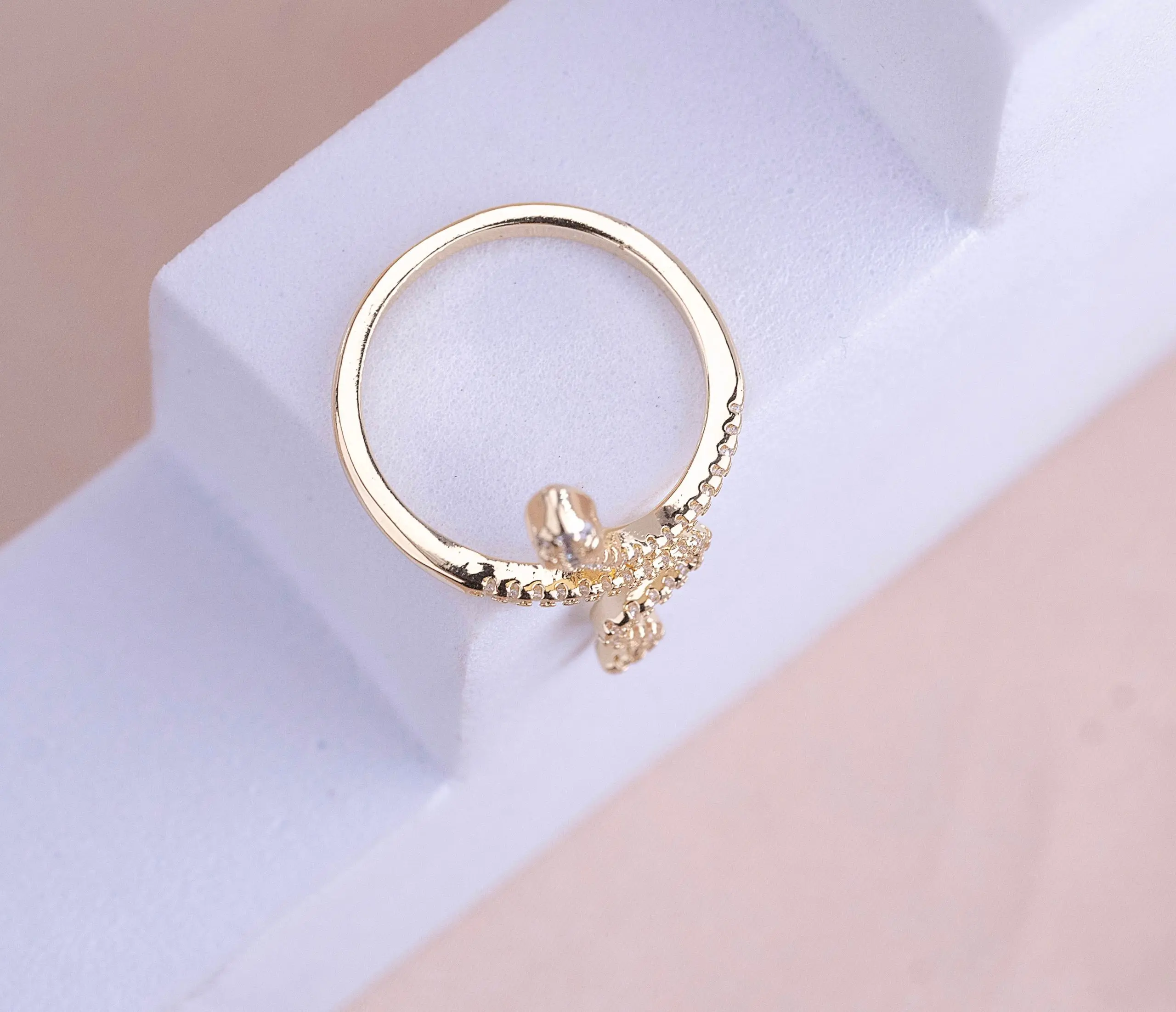 Anillo ajustable de cover gold con diseño de serpiente, banda con textura de cuentas y un micro circón brillante, sobre soporte blanco.