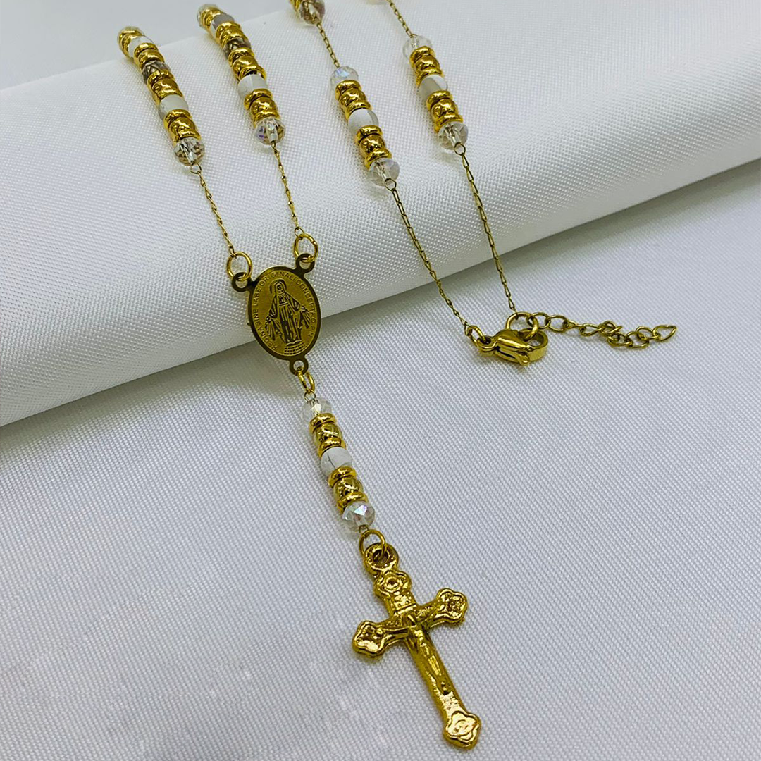 Camándula en baño de oro con cuentas de Murano blancas, argollas doradas, medalla ovalada y crucifijo ornamentado sobre fondo blanco.