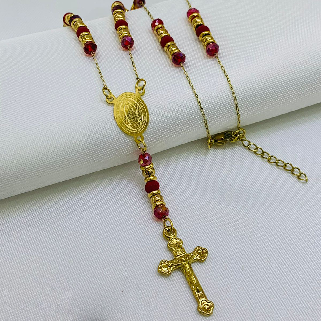 Camándula de baño de oro con cuentas de murano rojo, argollas doradas, medalla ovalada y crucifijo sobre fondo blanco.