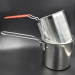 Olla freidora con cesta perforada de acero inoxidable, con mango de silicona roja, apoyada sobre fondo oscuro.