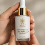 Manos sosteniendo un frasco de vidrio blanco de sérum facial Sine Mácula con gotero y tapa dorada, contenido de 30 ml.