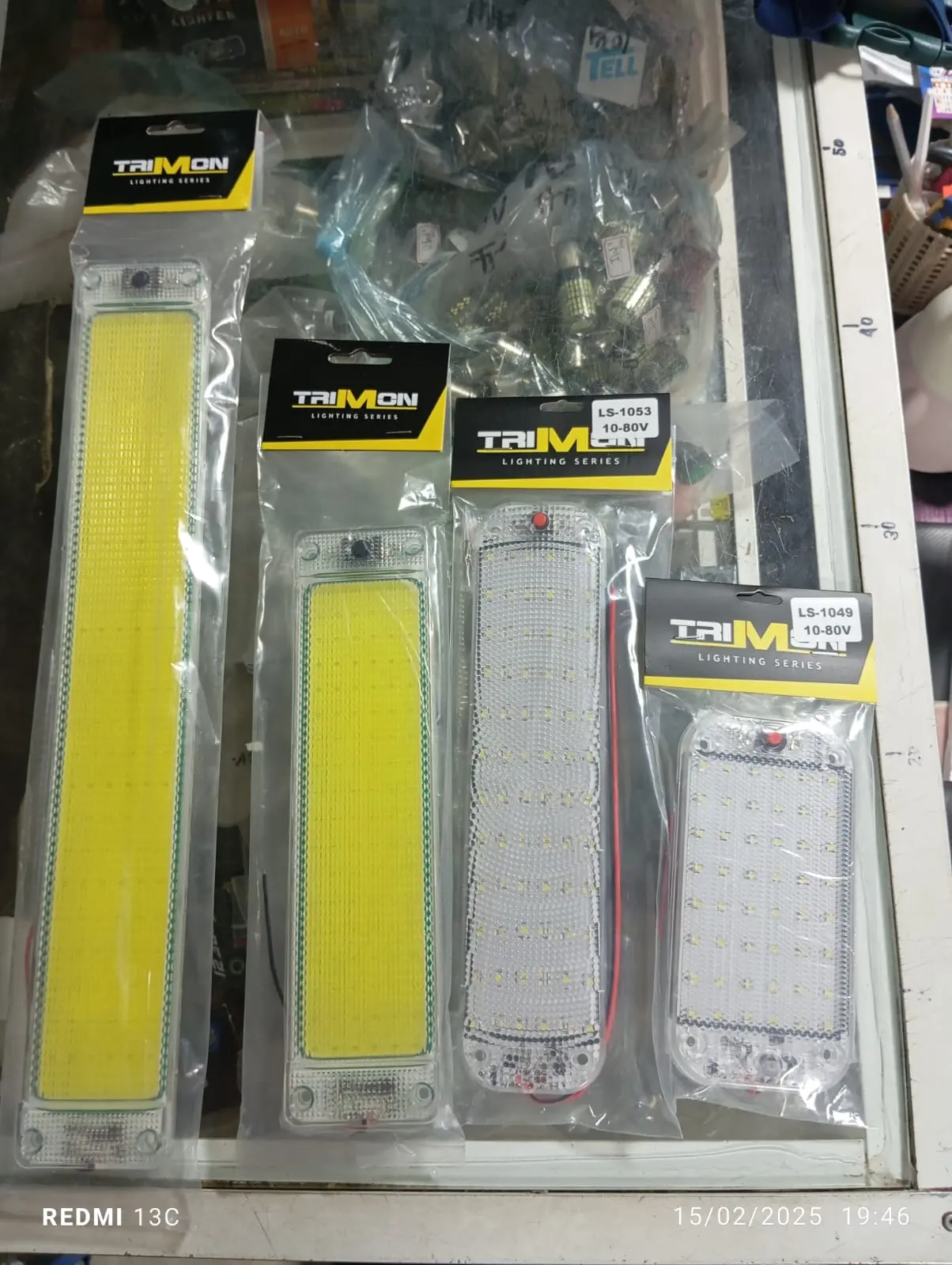 Cuatro tiras de luces LED empacadas verticalmente sobre una vitrina, ordenadas de mayor a menor tamaño, con empaques transparentes y cabezales negros con amarillo.