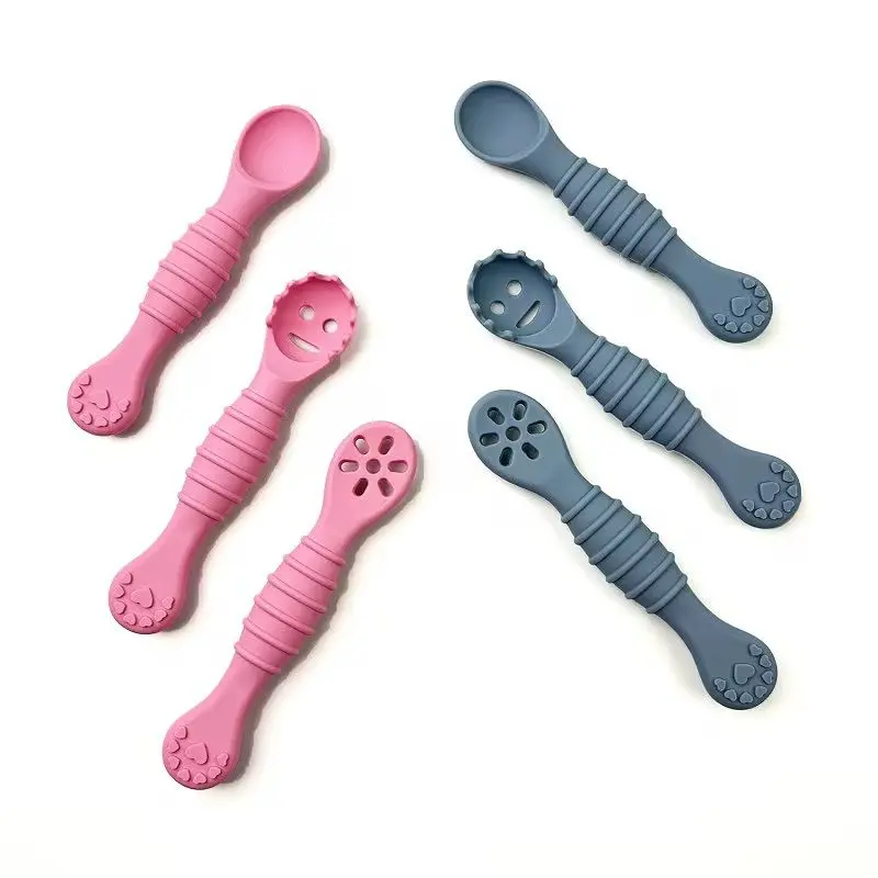 Seis cucharas de aprendizaje de silicona para bebé en colores rosa y gris, con texturas antideslizantes y cabezales sólidos, ranurados y perforados.