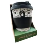 Mug de fibra de bambú con diseño de huellas de perro en blanco y negro, tapa y funda negra, sobre base verde con texto Love Eco, Love Life.