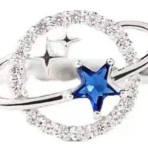 Anillo plateado con diseño de planeta y estrella central de cristal azul, rodeado por un aro con incrustaciones de brillantes y acabado pulido.