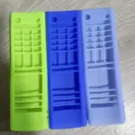 Tres fundas de silicona para control remoto LG clásico en colores verde claro, azul y lila, dispuestas sobre superficie de madera.