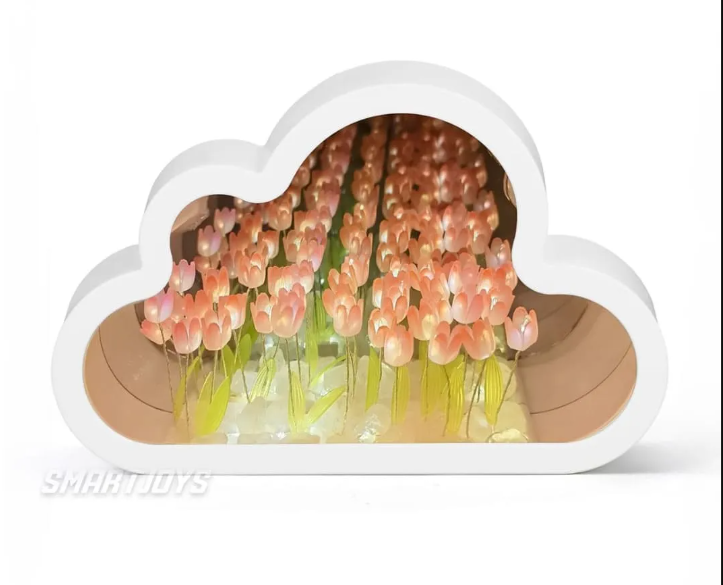 Lámpara espejo con forma de nube blanca, tulipanes rosados con tallos verdes sobre base de cristales y luz LED cálida.