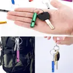 Silbato de aluminio verde para emergencias colgado en llavero junto a una llave sobre la palma de una mano, con vistas de uso en mochila y llavero múltiple.