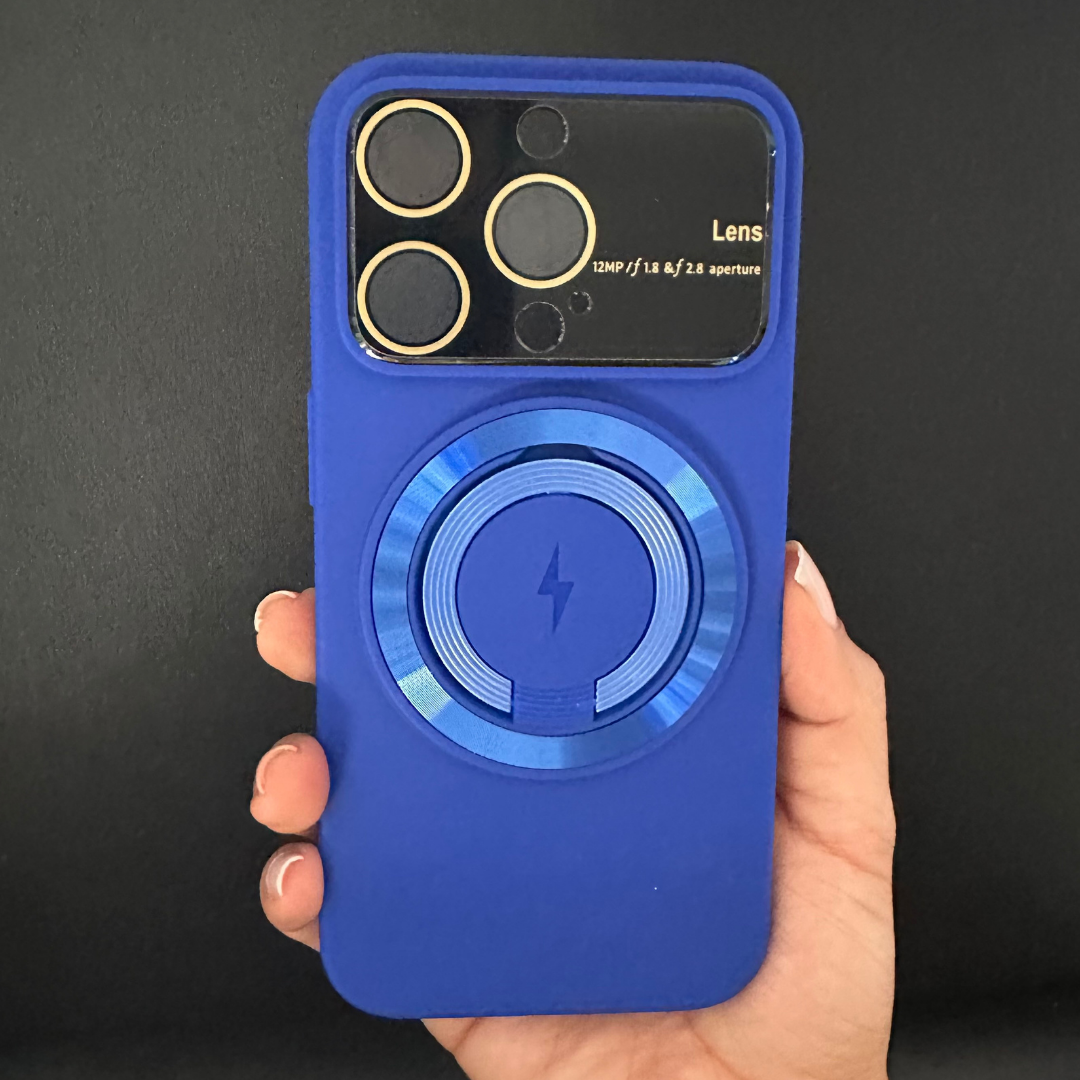 Funda azul de silicona con protector de lentes de bordes dorados y anillo MagSafe central con icono de rayo, sostenida por una mano.