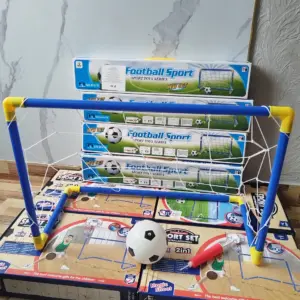 Miniportería de fútbol infantil azul y amarilla armada sobre cajas de cartón que incluyen balón, inflador y accesorios para juego 2 en 1 de interior.