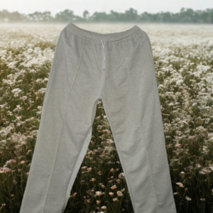 Pantalón bota recta de algodón perchado gris claro para mujer con cordón ajustable, sobre un campo de flores blancas y neblina.