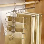Percha organizadora múltiple de acero inoxidable con cinco niveles para colgar pantalones, diseñada para ahorrar espacio vertical en el clóset.