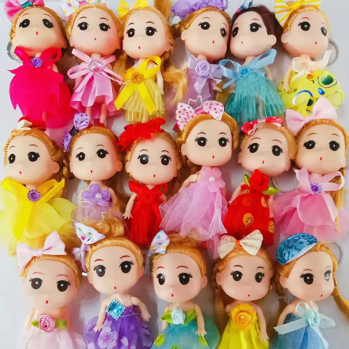 Llaveros de muñecas con vestidos de tul de colores, lazos decorativos y detalles brillantes, organizados en filas para decorar bolsos o accesorios.