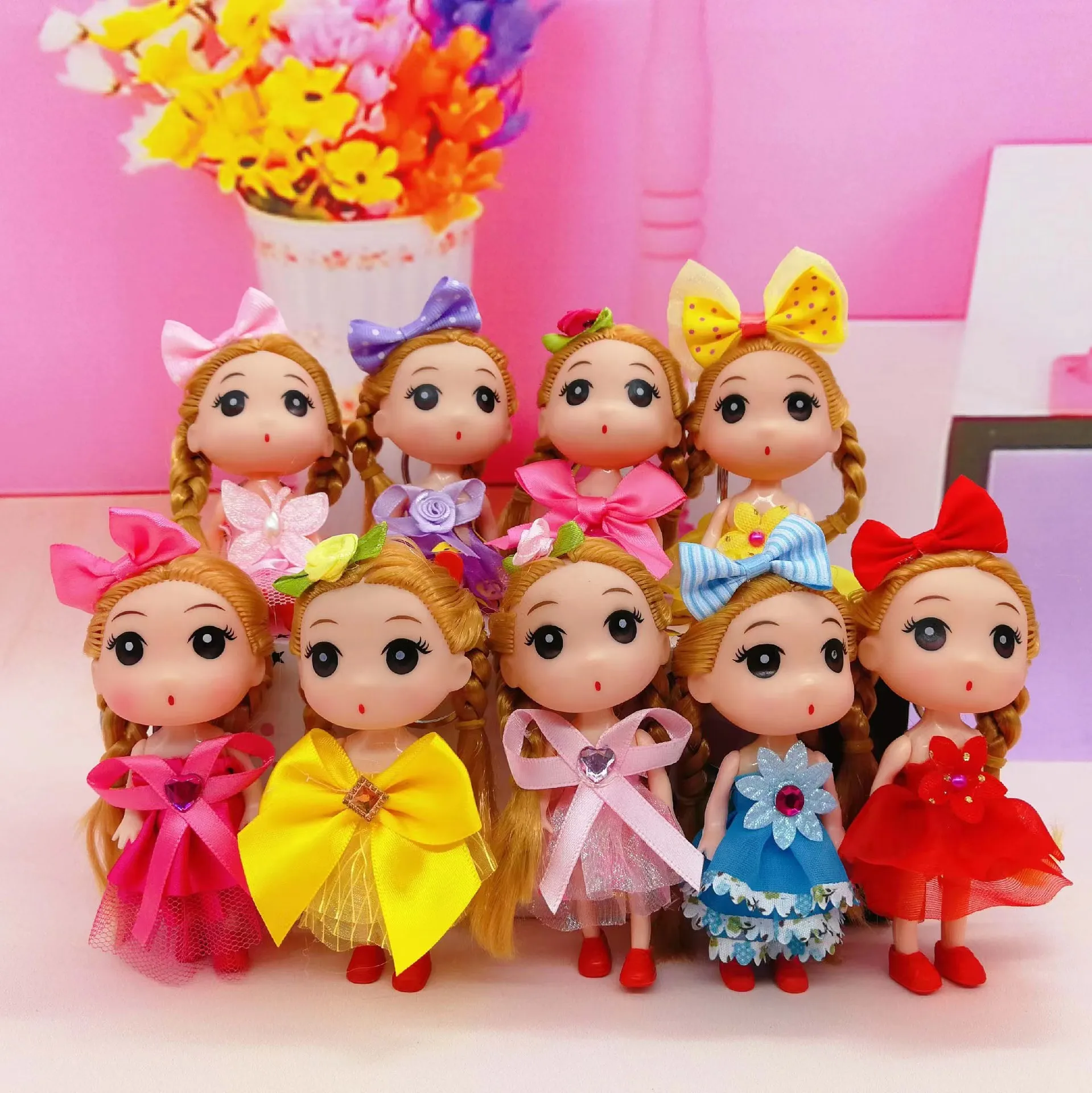 Conjunto de llaveros de muñecas decorativas con vestidos de colores, lazos grandes y cabello trenzado, ideales para personalizar bolsos con estilo tierno.