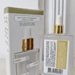 Sérum corporal hidratante en caja blanca con detalles dorados y frasco transparente de vidrio con gotero, notas de fresa, vainilla y ámbar.