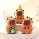 Llaveros de capibara en silicona café con detalles de patito amarillo y tortuga verde, dispuestos sobre bases blancas circulares.