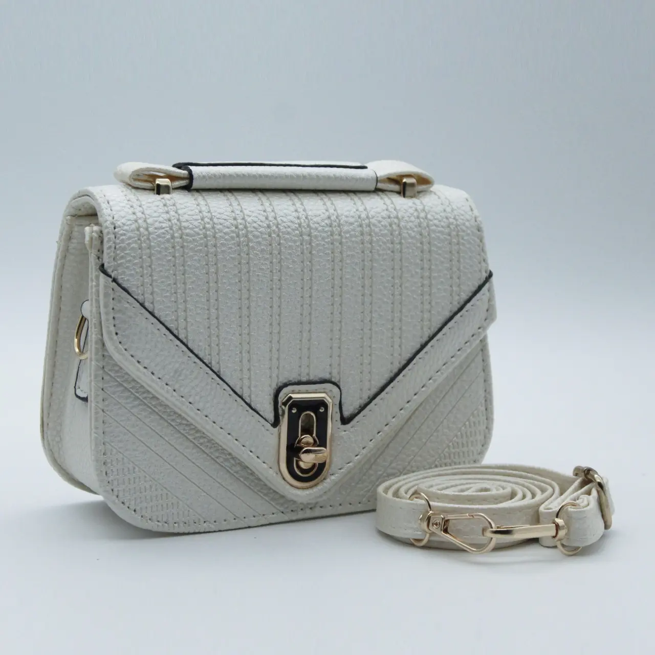 Bolso bandolera sintético color marfil con textura acanalada, solapa en V, broche metálico dorado y correa ajustable aparte.