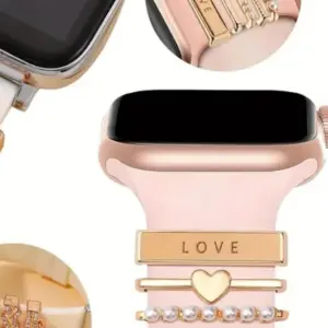 Cinco pasadores decorativos dorados en acero inoxidable sobre correa rosa para smartwatch, con dijes de "LOVE", corazón y perlas.