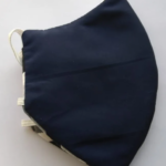 Tapabocas antifluido azul oscuro de tres capas con diseño ergonómico y elásticos laterales claros sobre fondo blanco