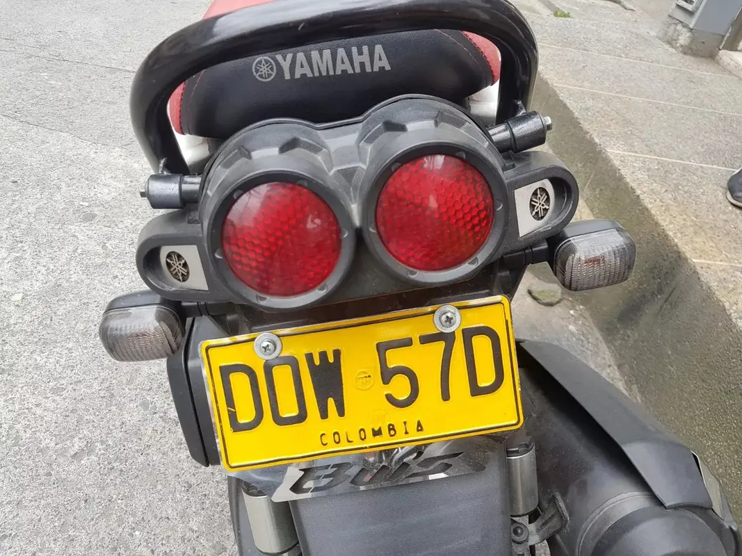 Vista posterior de Yamaha BWS con luces stop rojas circulares y los laterales de acero inoxidable instalados junto a la placa.