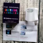 Caja morada de luz LED para inodoro de 8 colores, dispositivo blanco con sensor de movimiento y hoja de instrucciones sobre superficie de madera.