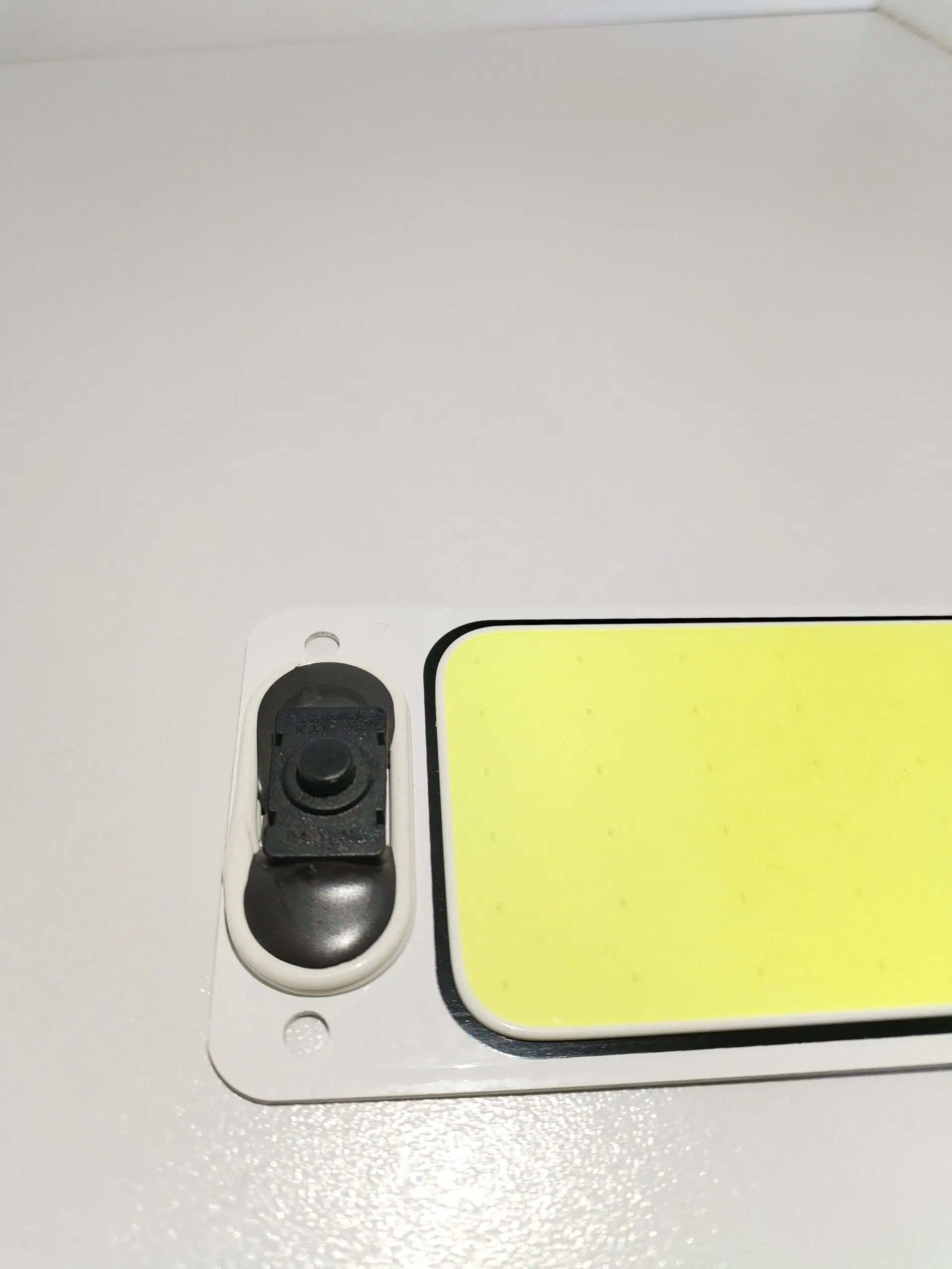 Plaqueta de techo LED blanca rectangular para vehículos con interruptor negro y superficie difusora de tono amarillento.