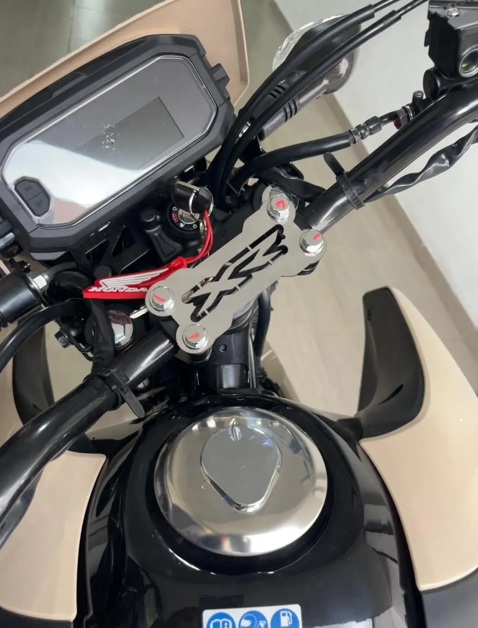 Soporte embellecedor de manubrio plateado en acero inoxidable para moto, instalado en la zona superior de dirección.