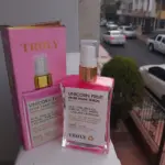 Sérum corporal rosado Unicorn Fruit After Shave de Truly Beauty en envase de vidrio transparente con dispensador dorado y su caja rosa de exhibición sobre superficie blanca.
