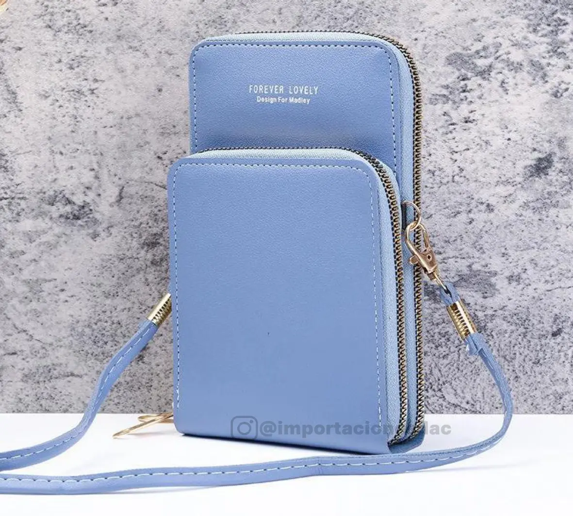 Bolso porta celular cruzado azul claro de cuero sintético con dos compartimentos independientes y correa ajustable.