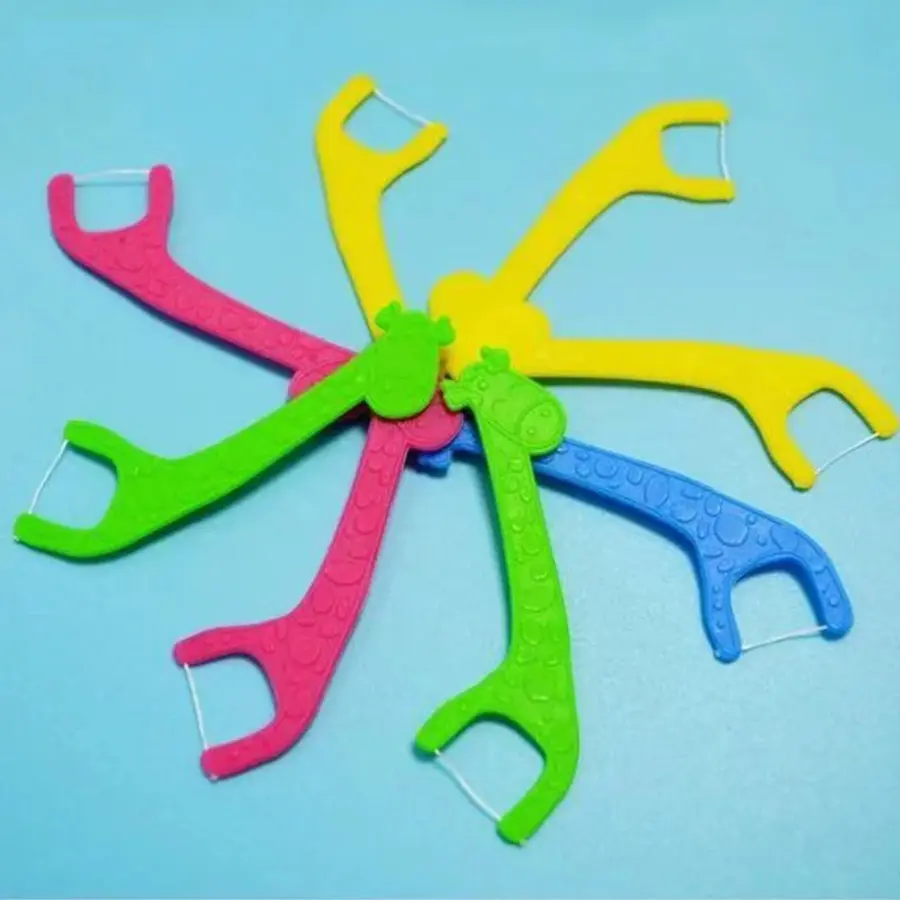 Set de hilos dentales infantiles en forma de jirafa coloridos, dispuestos en círculo sobre fondo azul claro