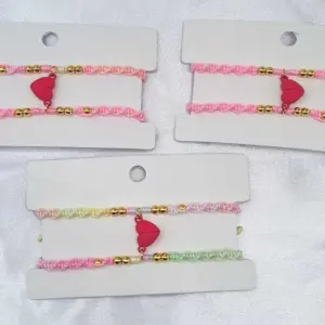 Set de 4 pulseras magnéticas rosadas y multicolores para parejas, con tejido en macramé, cuentas doradas y un dije central de corazón con cierre imantado.