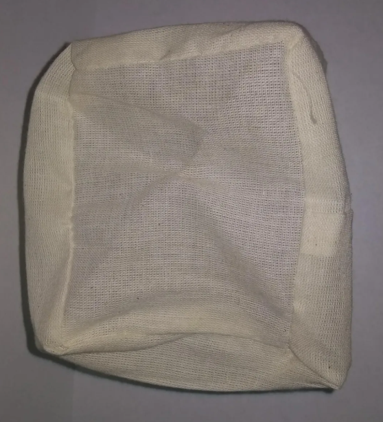 Filtro de tela color crema con trama tejida visible para greca cafetera, diseñado para retener sedimentos y obtener café claro.