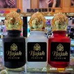 Tres botellas de perfume árabe con atomizador dorado y tapa decorada, en colores negro, blanco y rojo, con etiqueta de la marca Najah Perfum.