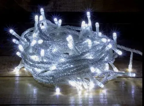 Guirnalda de 100 luces LED blancas enrollada sobre superficie de madera, ideal para decoración navideña en interiores y exteriores.