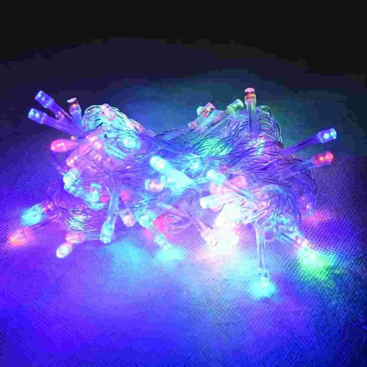 Serie de luces LED navideñas con 100 bombillas multicolores dispuestas en un ovillo, ideales para decoración interior y exterior con cable transparente.