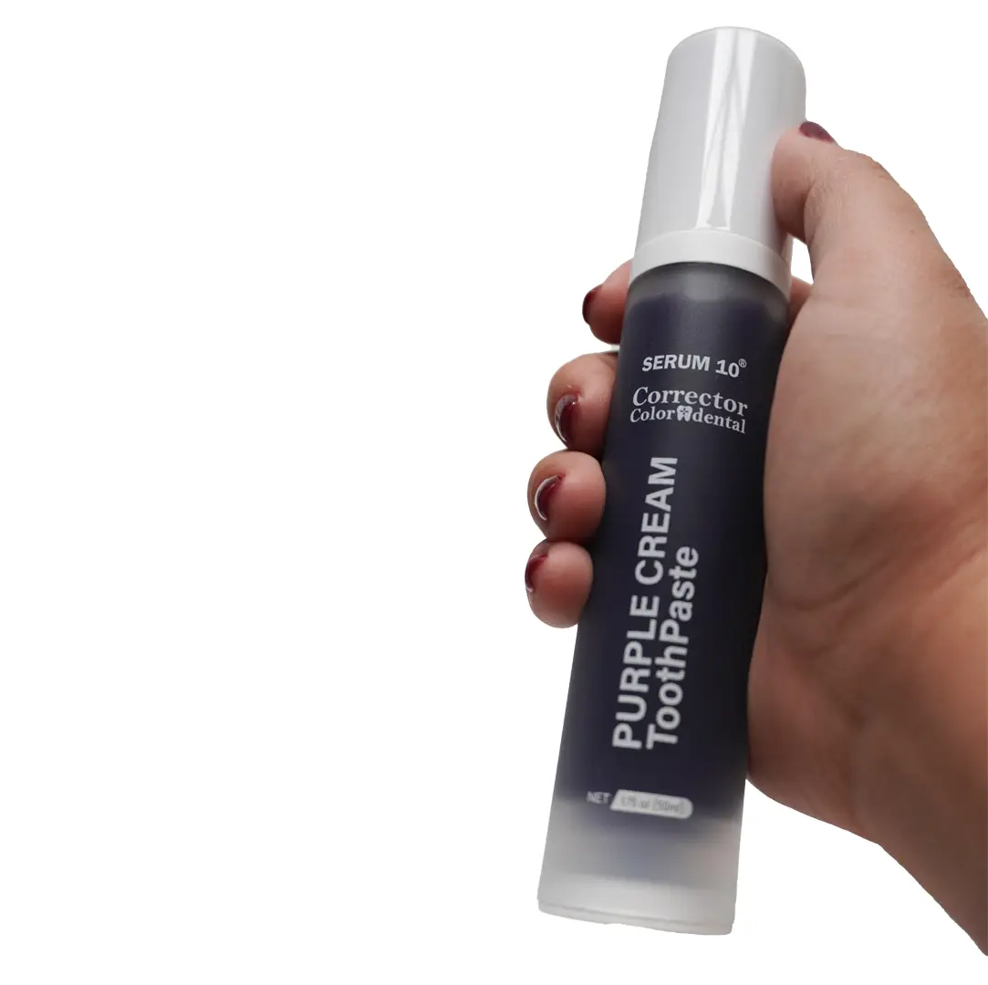 Mano sosteniendo envase dispensador cilíndrico de sérum corrector dental morado blanqueador de 50 ml con etiqueta oscura y tapa blanca.